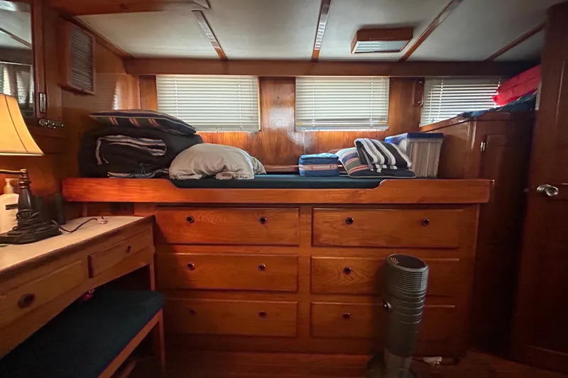 Slide: The Image of Cozy 1976 Bristol Trawler cabin with wooden drawers, desk, and neatly stacked linens. - 29