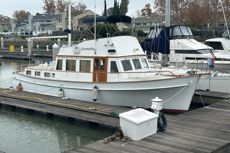 Slide: The Image of 1976 Bristol Trawler docked at a marina, surrounded by other boats and waterfront homes. - 3
