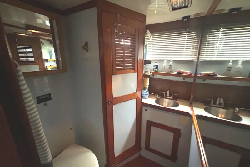 Slide: The Image of 1976 Bristol Trawler bathroom with dual sinks, wooden cabinetry, and mirrored walls. - 32