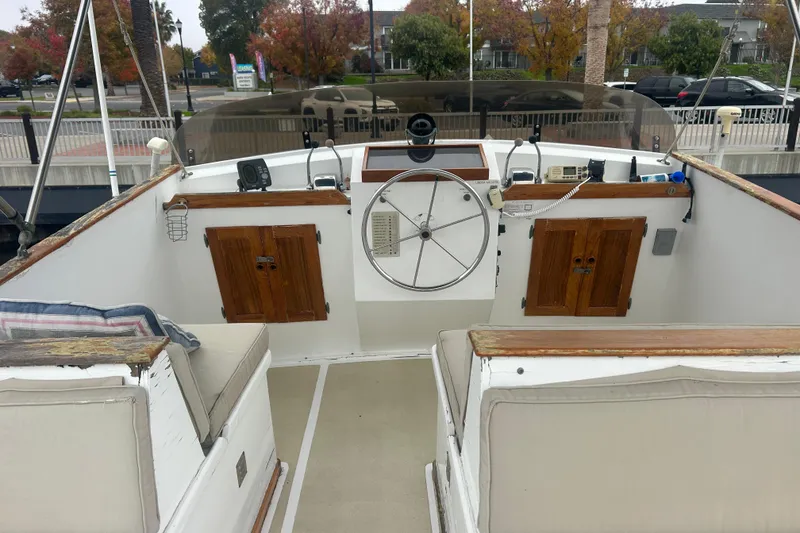 Slide: The Image of 1976 Bristol Trawler helm with wooden accents and steering wheel, docked in a marina. - 40