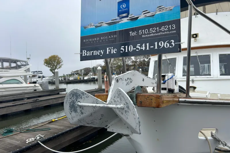 Slide: The Image of 1976 Bristol Trawler with anchor, docked at marina, featuring yacht brokerage sign. - 50
