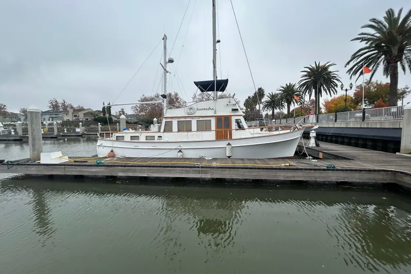 Slide: The Image of 1976 Bristol Trawler docked at a marina with palm trees in the background. - 60