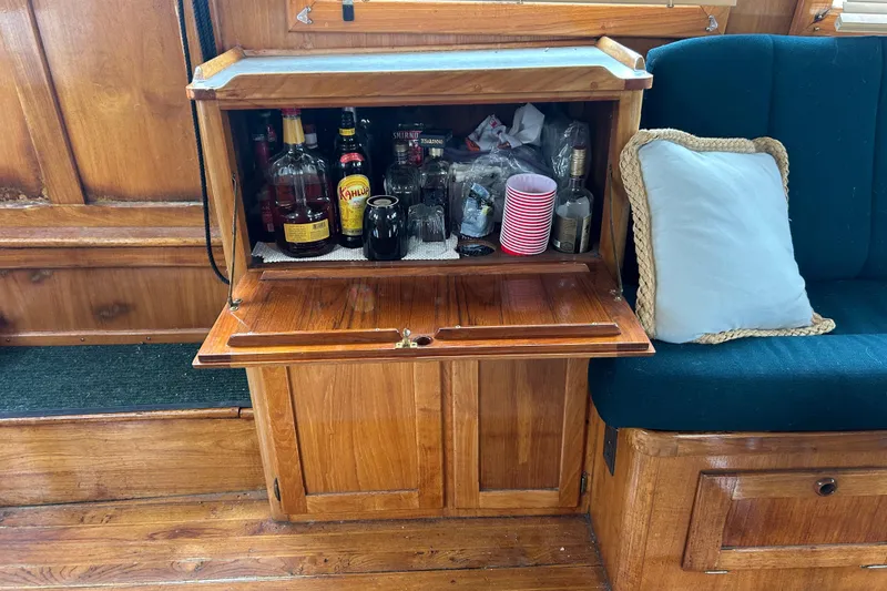Slide: The Image of Wooden bar cabinet on 1976 Bristol Trawler, stocked with liquor bottles and glasses. - 9
