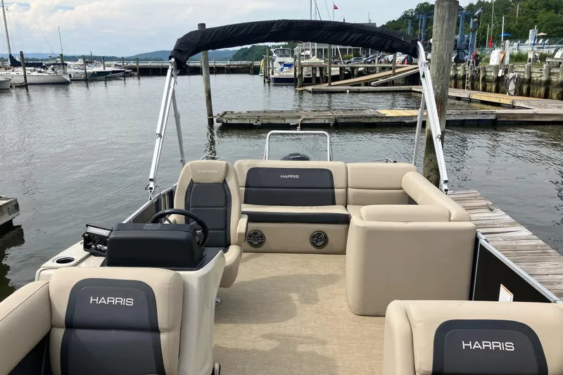 Slide: The Image of 2024 Harris HCX23 pontoon boat docked at marina, featuring spacious seating and modern design. - 5