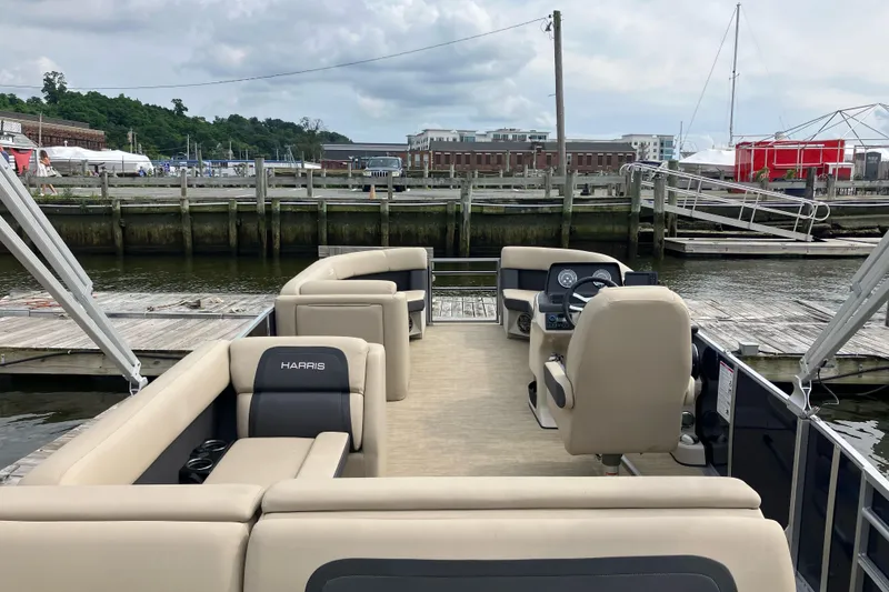 Slide: The Image of 2024 Harris HCX23 pontoon boat docked at a marina with plush seating. - 6