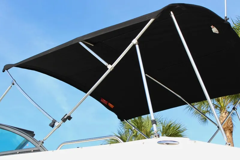 Slide: The Image of 2024 NauticStar 203 DC Deck boat with black bimini top against blue sky. - 15
