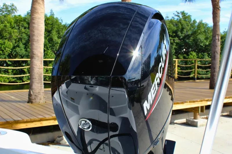 Slide: The Image of 2024 NauticStar 203 DC Deck boat with Mercury outboard engine, docked near palm trees. - 20