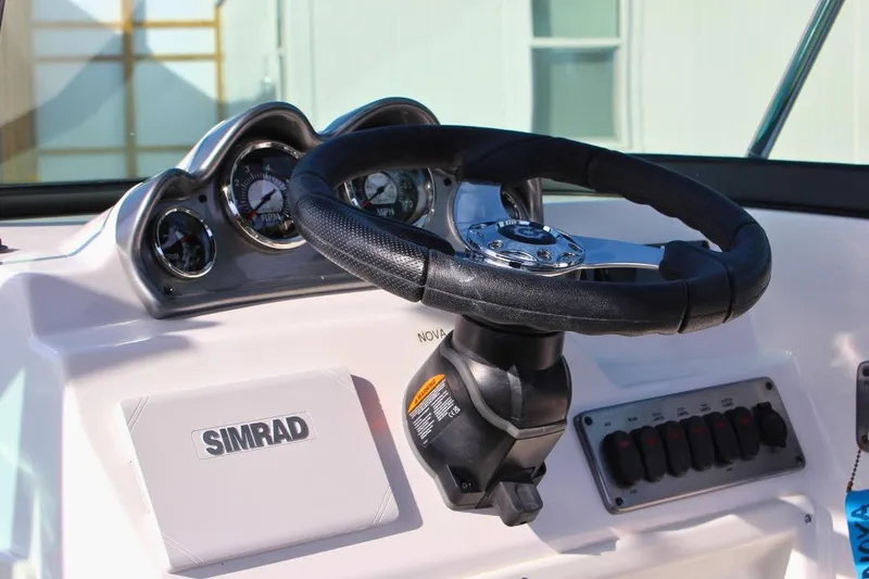 Slide: The Image of 2024 NauticStar 203 DC Deck boat dashboard with steering wheel and Simrad display. - 21
