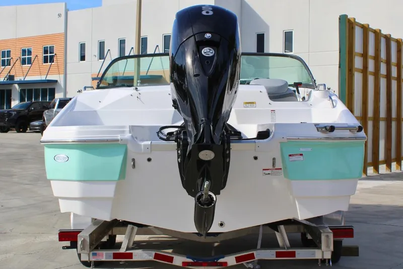 Slide: The Image of 2024 NauticStar 203 DC Deck boat on trailer, rear view with outboard motor. - 3