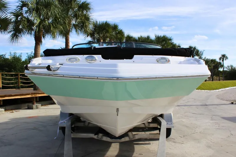 Slide: The Image of 2024 NauticStar 203 DC Deck boat on trailer, surrounded by palm trees. - 7