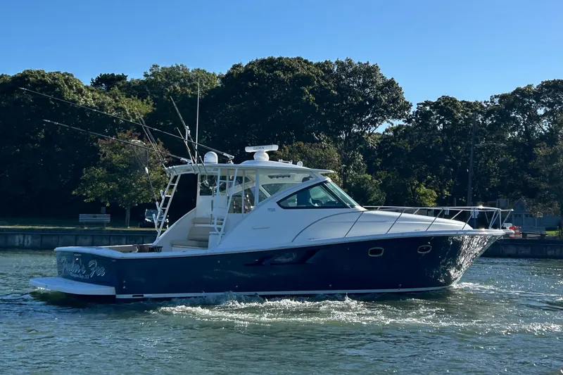 Slide: The Image of 2022 Tiara Yachts 43 Open cruising on a sunny day near a wooded shoreline. - 2