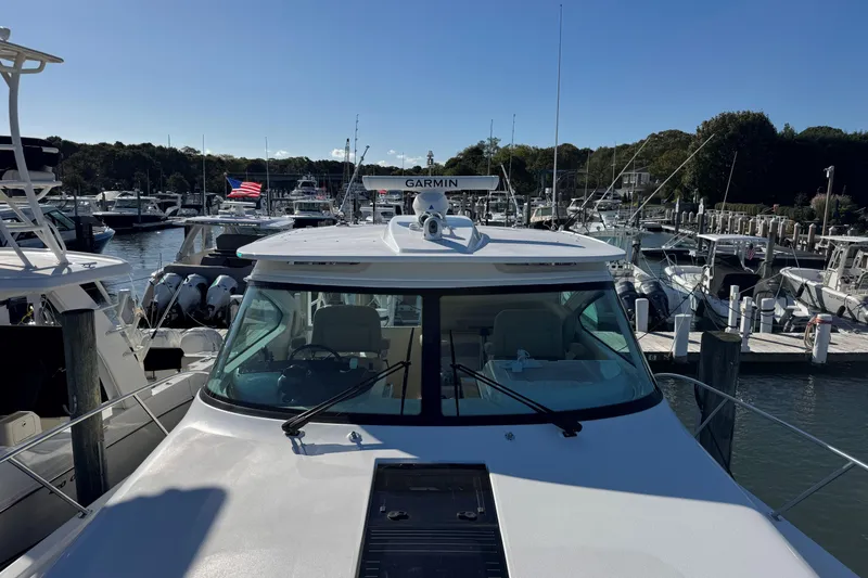 Slide: The Image of 2022 Tiara Yachts 43 Open docked at marina, clear sky, American flag visible. - 48