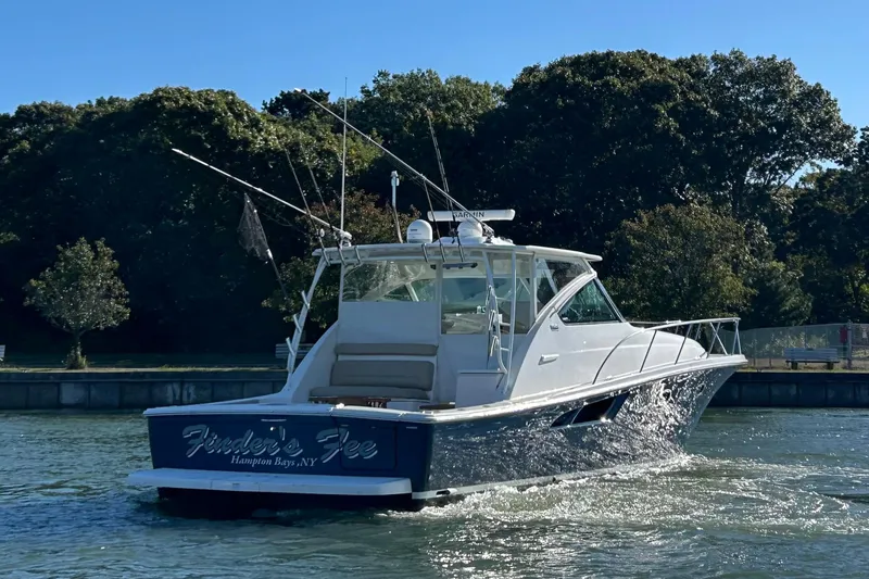 Slide: The Image of 2022 Tiara Yachts 43 Open cruising on a sunny day near lush greenery. - 52