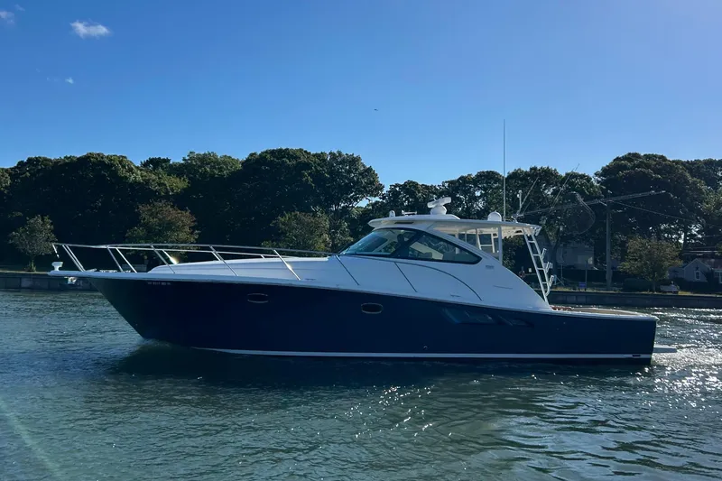 Slide: The Image of 2022 Tiara Yachts 43 Open cruising on a sunny day, surrounded by trees. - 53