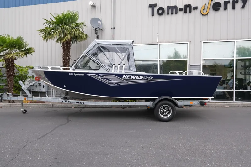 Slide: The Image of 2025 Hewescraft 200 Sportsman boat on trailer outside dealership. - 2