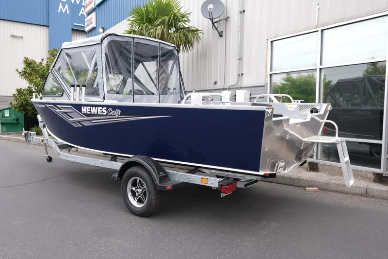 Slide: The Image of 2025 Hewescraft 200 Sportsman boat on trailer, parked outside a building. - 4