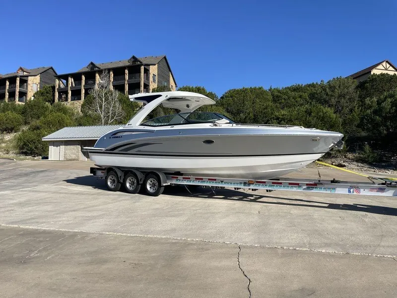 The Image of 2025 Formula 310 Bowrider on trailer, parked outdoors with buildings in the background. - 1