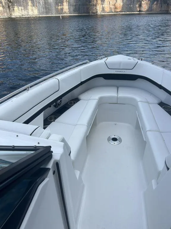 Slide: The Image of 2025 Formula 290 Bowrider boat with spacious seating, docked by a serene lake. - 17