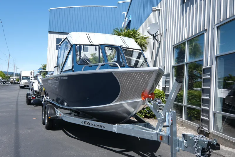 Slide: The Image of 2025 Hewescraft 210 Sea Runner ET boat on trailer outside a modern building. - 3