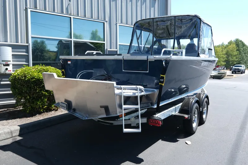 Slide: The Image of 2025 Hewescraft 210 Sea Runner ET boat on trailer, parked outside a building. - 4