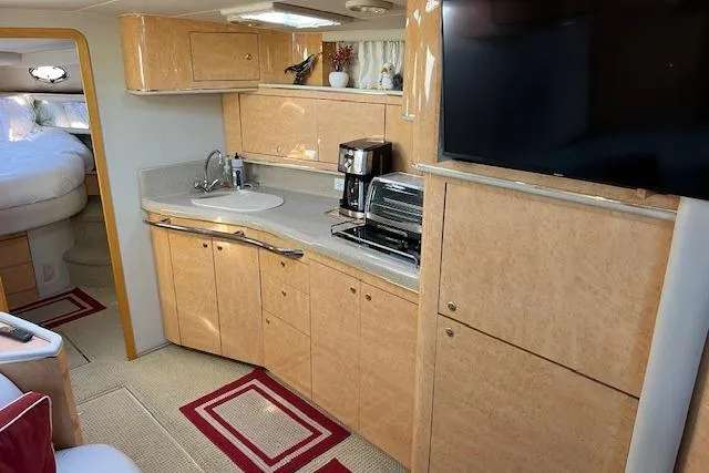 Slide: The Image of 1997 Sea Ray 450 Sundancer yacht interior with kitchenette, TV, and cozy sleeping area. - 37