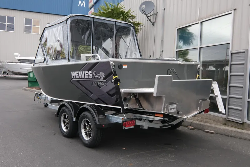 Slide: The Image of 2026 Hewescraft 180 ProV ET boat on trailer, parked outside industrial building. - 3