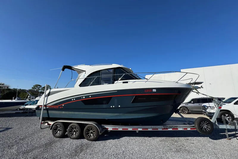 The Image of 2020 Beneteau Antares 27 boat on trailer, parked outdoors under clear blue sky. - 1