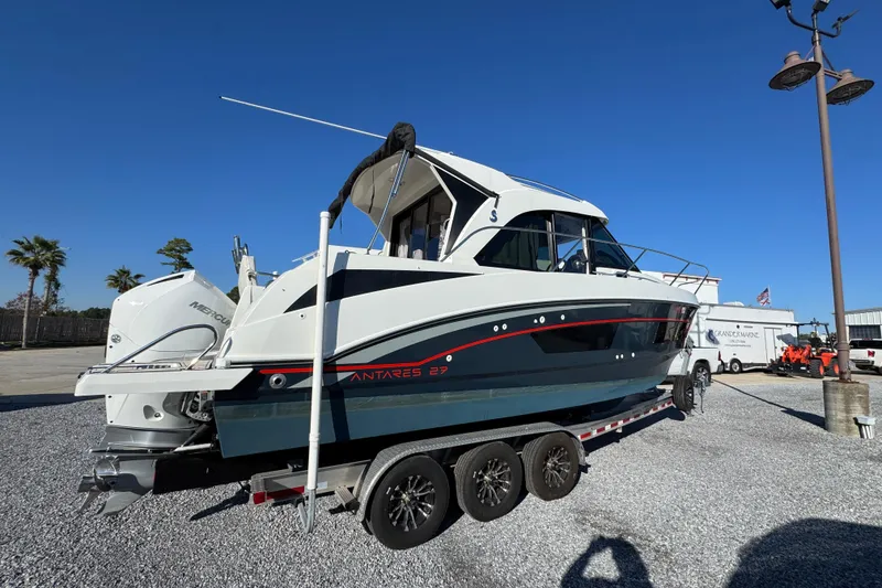 Slide: The Image of 2020 Beneteau Antares 27 boat on trailer, parked outdoors under clear blue sky. - 16