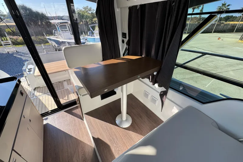 Slide: The Image of Interior of 2020 Beneteau Antares 27 boat with wooden table and seating area. - 33
