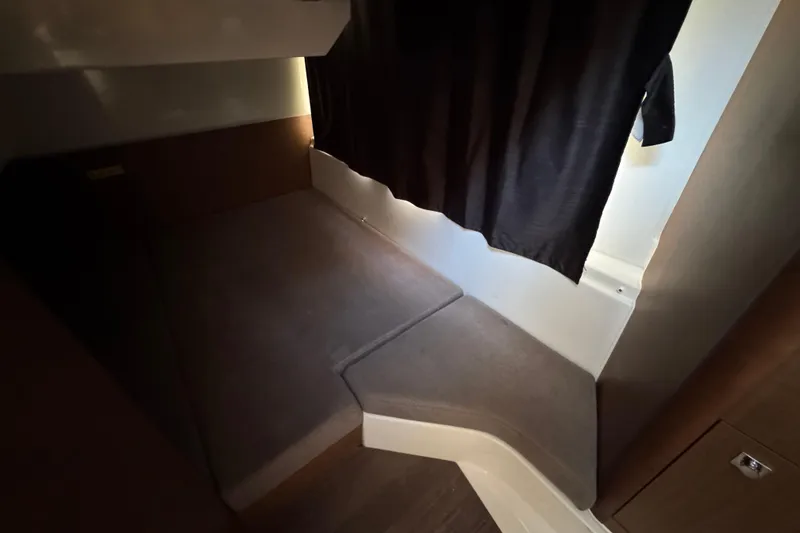 Slide: The Image of Cozy interior cabin of 2020 Beneteau Antares 27 with dark curtains and carpeted flooring. - 39