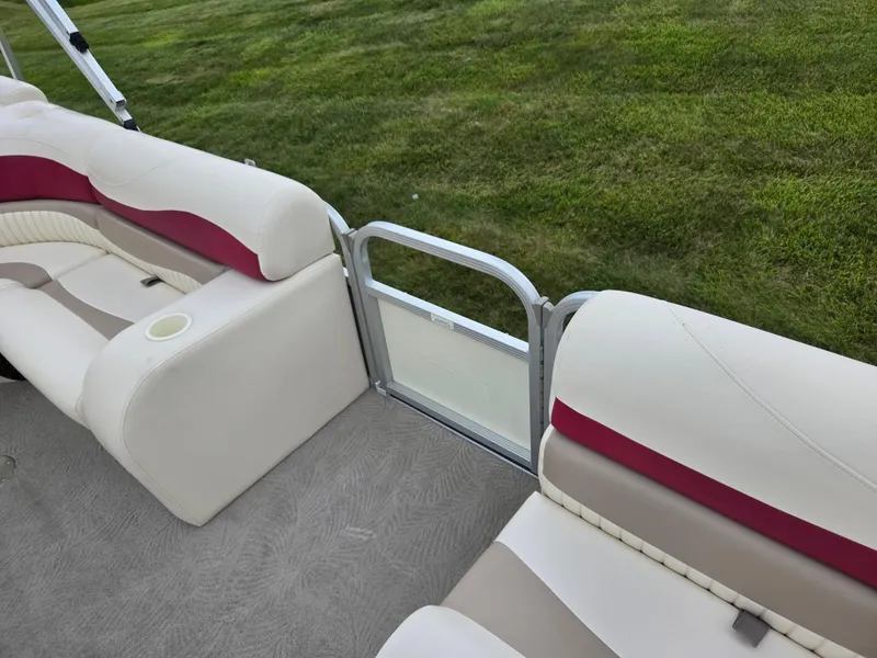 Slide: The Image of 2007 Bennington 2075GL boat interior with beige and red seating, grassy background. - 11