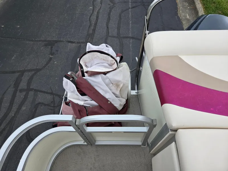 Slide: The Image of 2007 Bennington 2075GL boat with maroon and white seating, docked with a bag on board. - 15