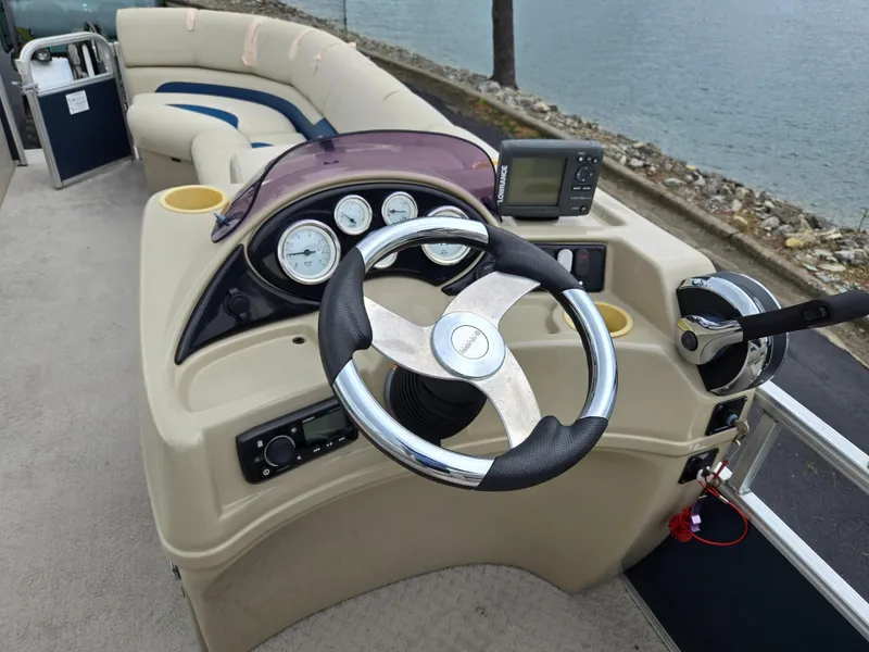 Slide: The Image of 2014 Lowe SS230 Super Sport boat dashboard with steering wheel and gauges by the water. - 21