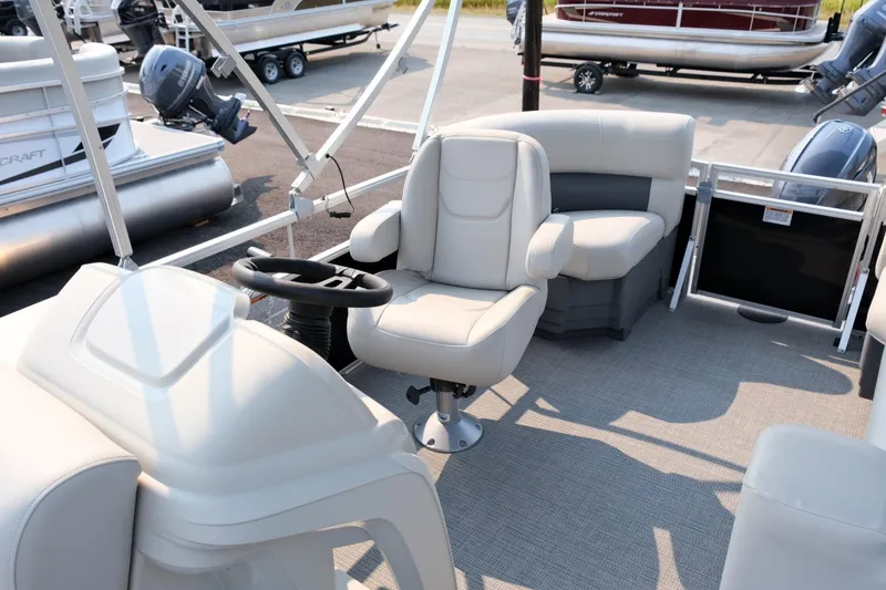 Slide: The Image of 2023 Starcraft LX 18 R pontoon boat interior with captain's chair and seating area. - 10