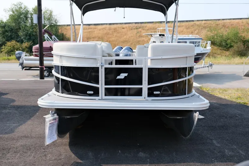 Slide: The Image of 2023 Starcraft LX 18 R pontoon boat, black and white, parked outdoors. - 3
