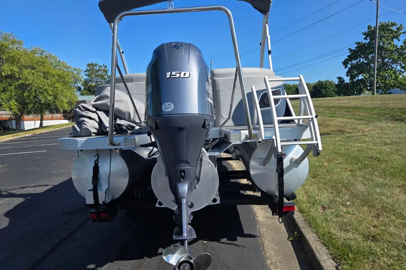 Slide: The Image of 2022 Bennington L 22 Quad Bench pontoon boat with 150 HP engine, parked outdoors. - 2