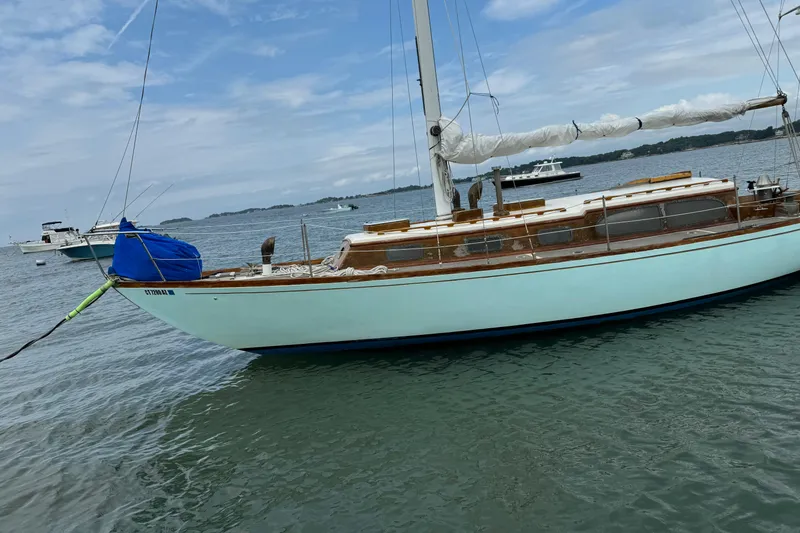Slide: The Image of 1960 Alden Challenger 38 sailboat moored on calm waters under a cloudy sky. - 3
