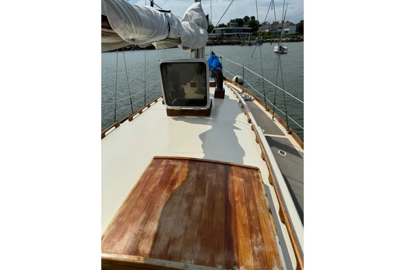 Slide: The Image of 1960 Alden Challenger 38 sailboat deck with wooden details, docked in a serene harbor. - 9