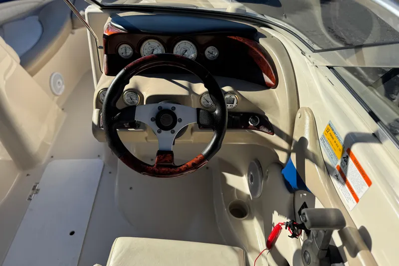 Slide: The Image of 2004 Glastron GX 235 boat cockpit with steering wheel and dashboard controls. - 21