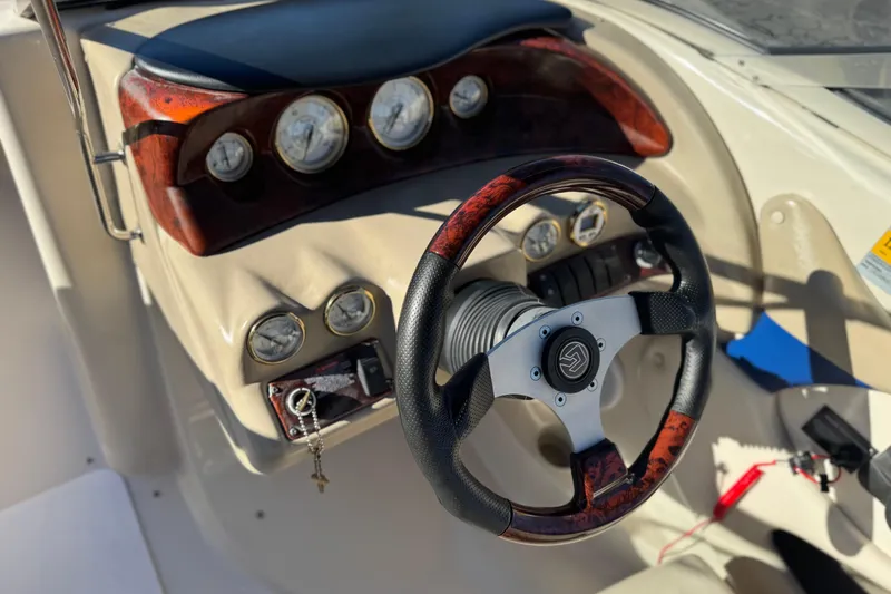 Slide: The Image of 2004 Glastron GX 235 boat dashboard with wood accents and steering wheel. - 22