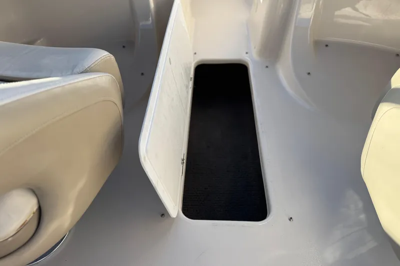 Slide: The Image of 2004 Glastron GX 235 boat interior with open storage compartment and beige seating. - 23