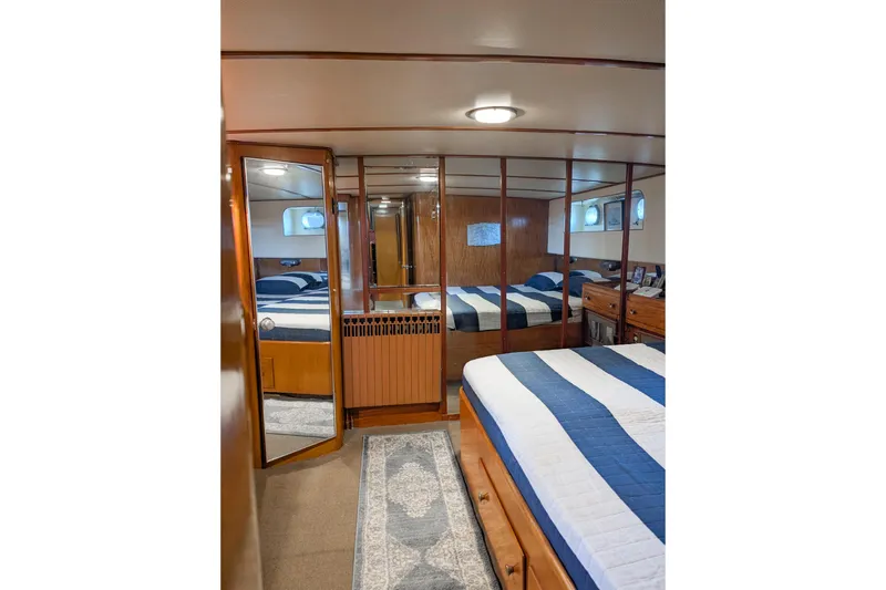 Slide: The Image of Luxurious boat cabin with striped bedding, wooden decor, and mirrored closet doors. - 19