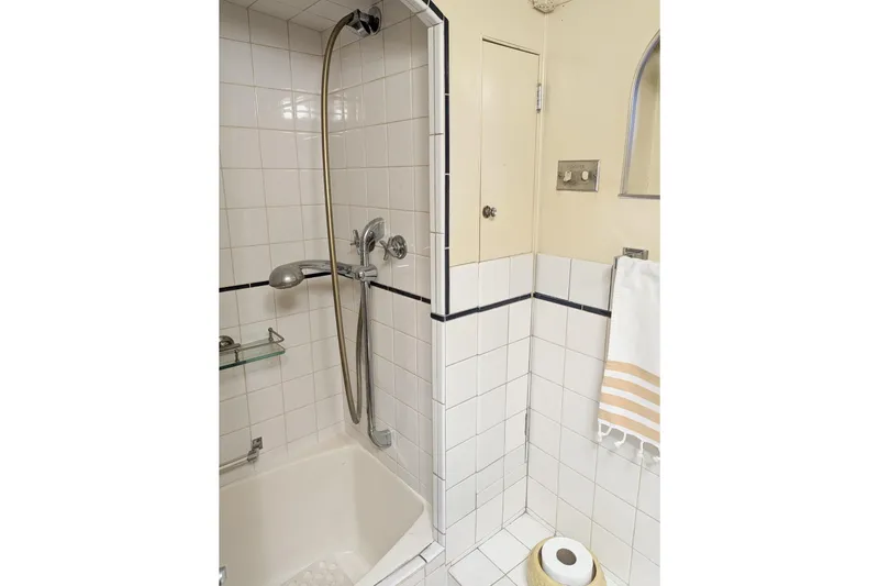 Slide: The Image of Vintage bathroom with tiled shower, handheld showerhead, towel, and toilet paper. - 24