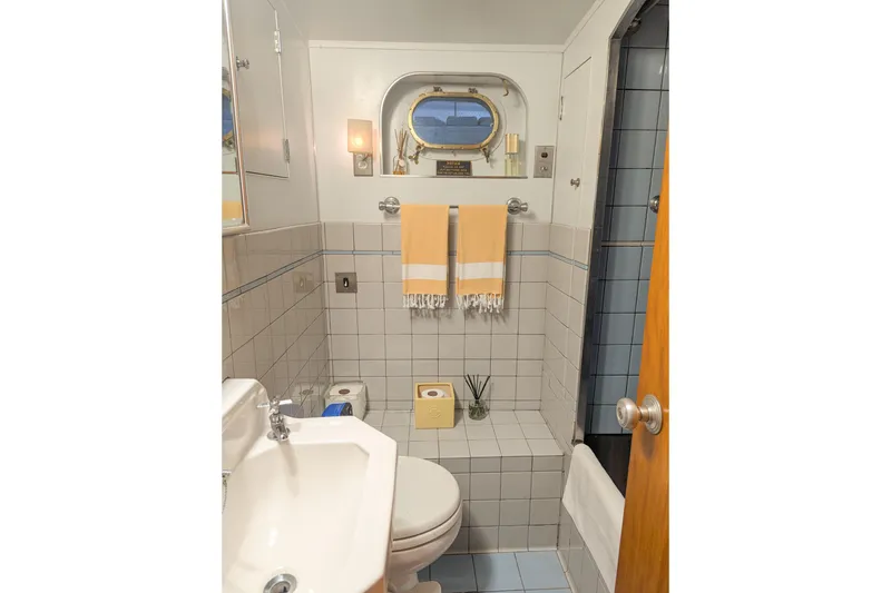 Slide: The Image of Compact bathroom with nautical decor, featuring porthole window and tiled walls. - 25