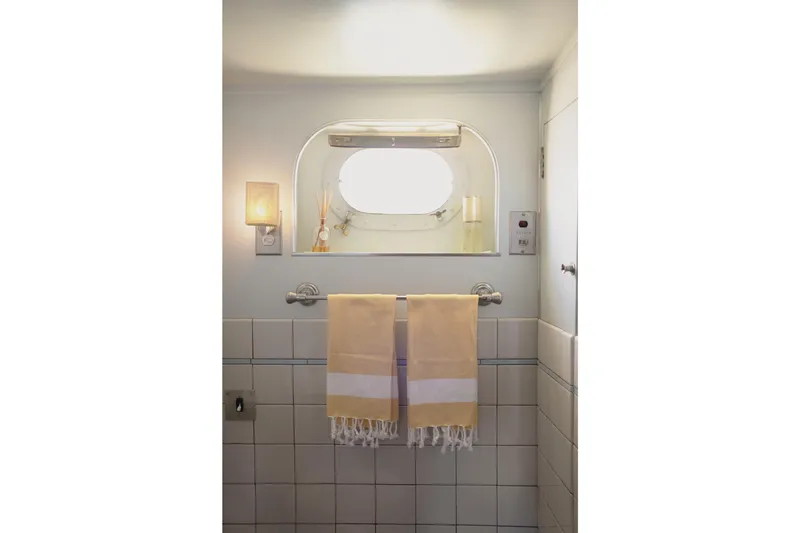 Slide: The Image of Vintage bathroom with yellow towel, porthole window, and soft lighting, inside a 1954 Grebe Sedan. - 28