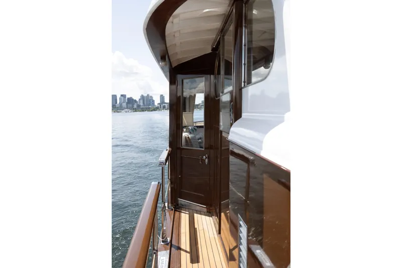 Slide: The Image of Side view of a classic boat with wooden deck, city skyline in background. - 34