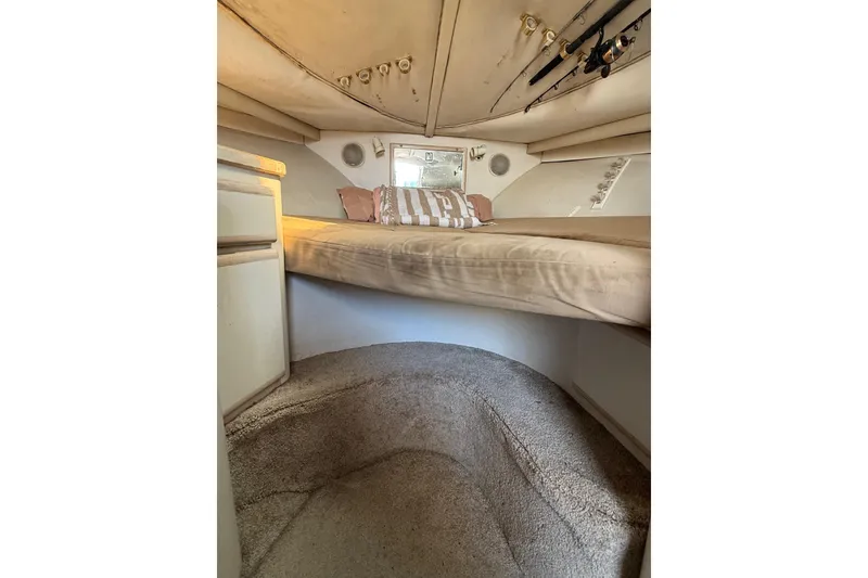 Slide: The Image of 1995 Blackfin 31 Combi cabin interior with bed, fishing rods, and storage. - 27