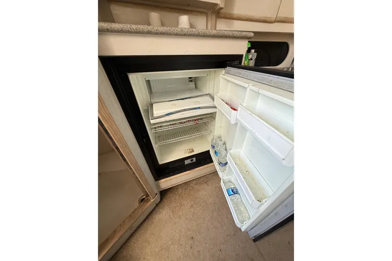 Slide: The Image of Open refrigerator inside 1995 Blackfin 31 Combi boat, containing water bottles and minimal items. - 34