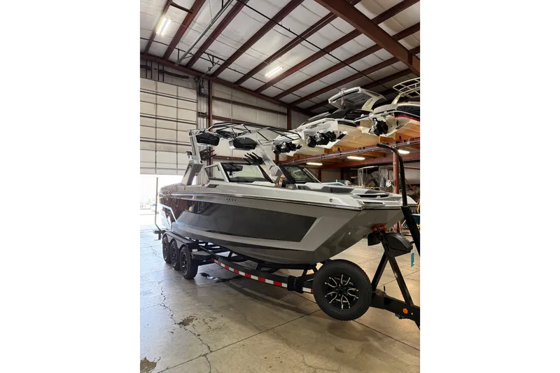 Slide: The Image of 2026 MasterCraft XStar 25 boat on trailer in indoor storage facility. - 2