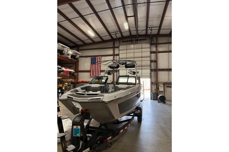 Slide: The Image of 2026 MasterCraft XStar 25 boat in warehouse with American flag backdrop. - 3